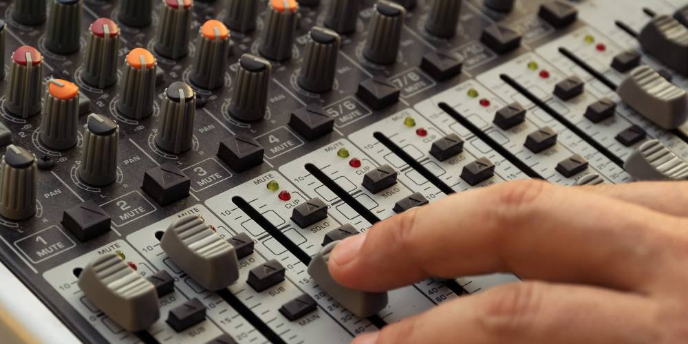 A sound mixer's fingers on a sound board slider